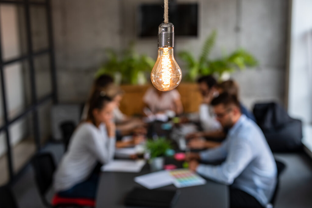 Young business people are discussing together a new startup project. A glowing light bulb as a new idea.