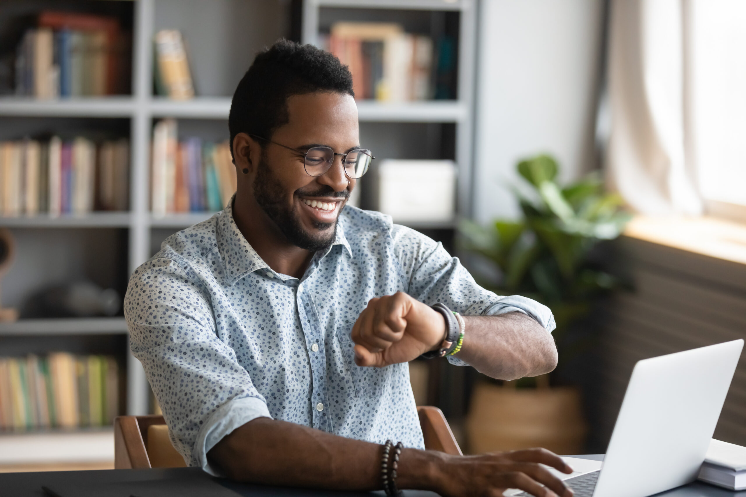 businessman employee worker looking at smart watch sit at office desk with laptop,